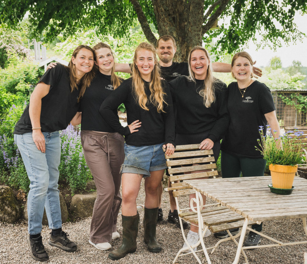 Ansatte på Lundbergs Planteskole smiler i sola ved siden av kafeen på Lundbergs Planteskole