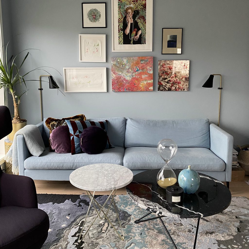 Blå sofa i en stue med vakre bilder på veggen. Foto