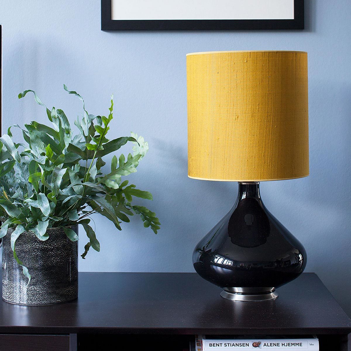 Flavia bordlampe med gul skjerm fra Thawaru stående på en benk utstilt for eske interiør