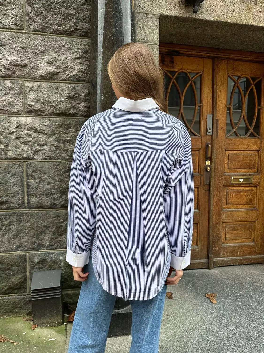 Jente viser frem en stripete blå og hvit skjorte bakfra