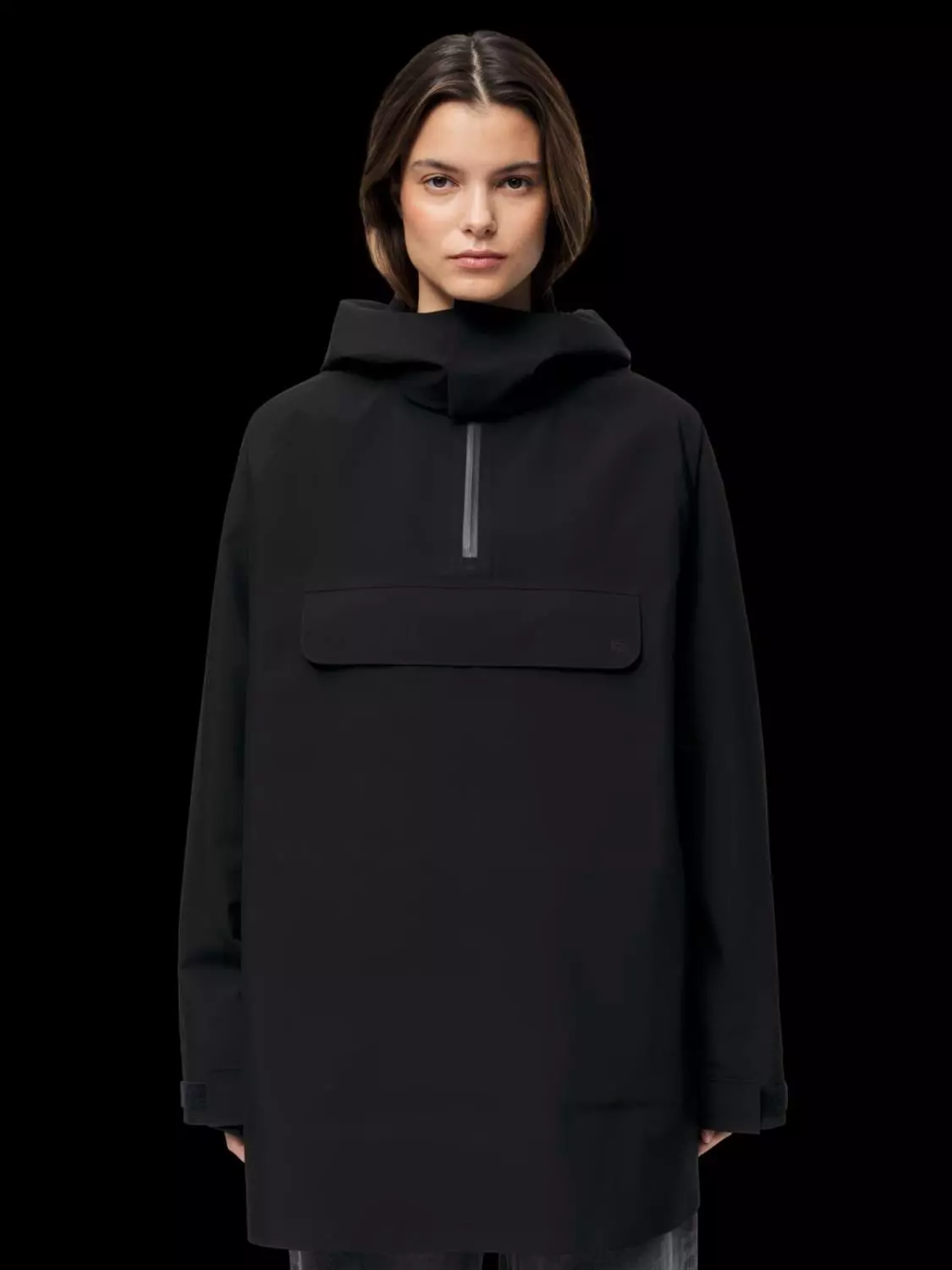 Jente viser frem an svart regnponcho. Det er svart bakgrunn og jenten smiler ikke